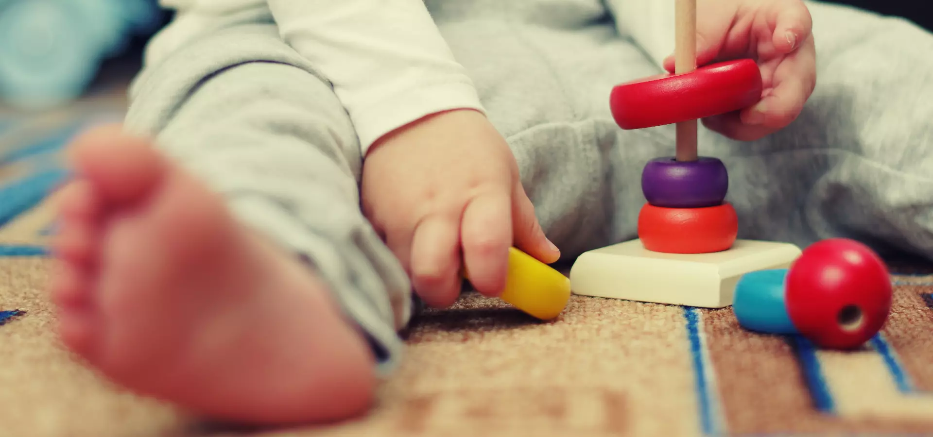 Toddler playing with wooden stacking toys.