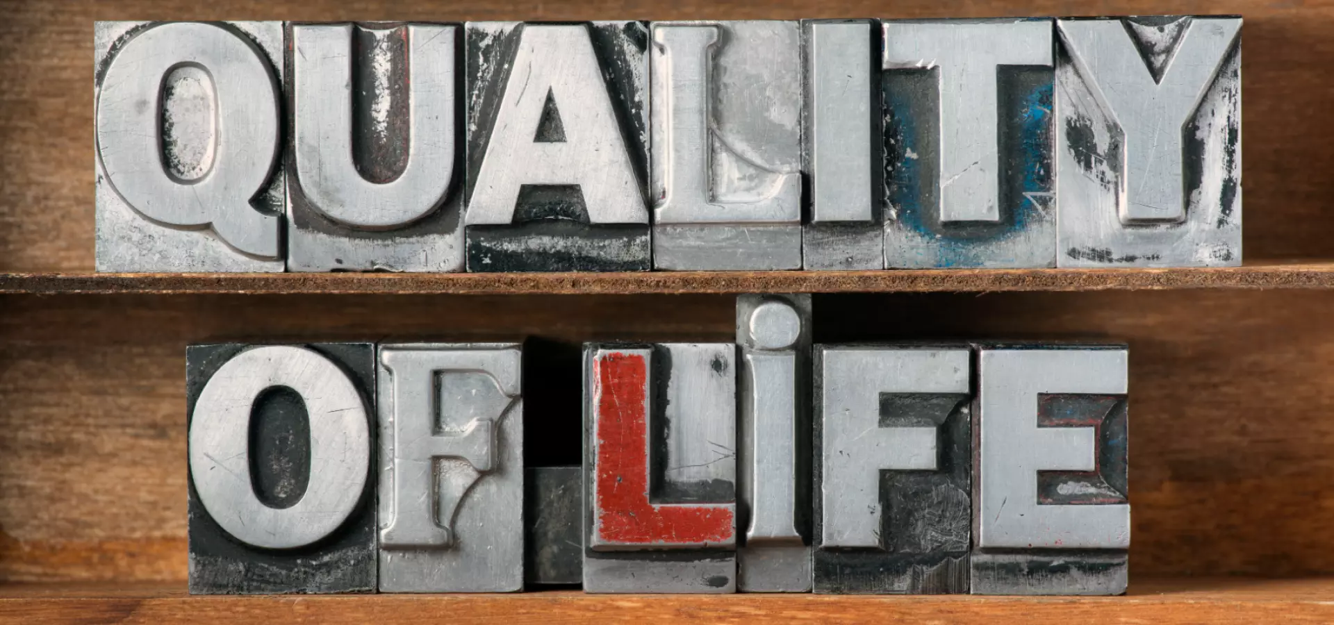 Metallic letterpress letters spelling the words 'Quality of life' on a wooden background.