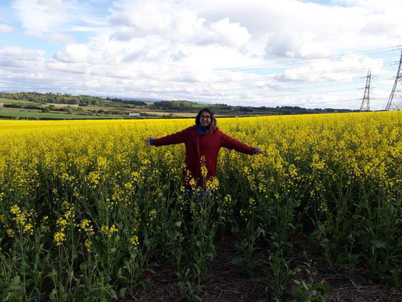 Shruti standing in a field of yellow flowers