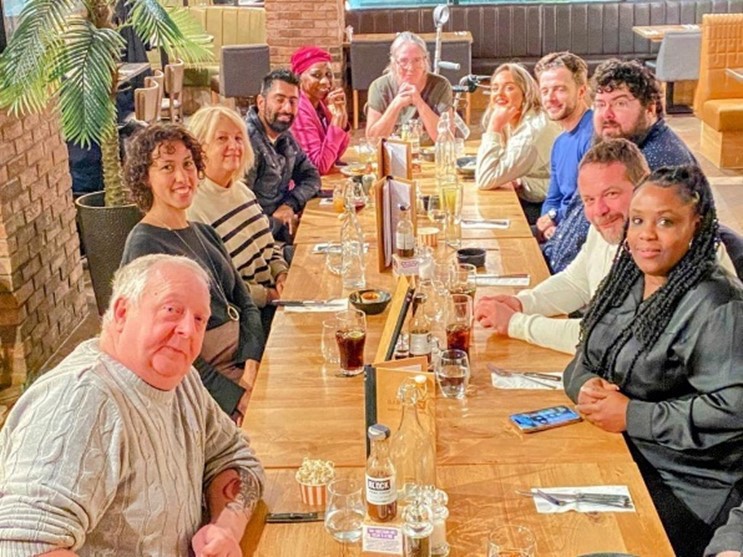 Participants of CHA Lived Experience Panel sitting at a long dinner table, with drinks and cutlery beside each participant. 