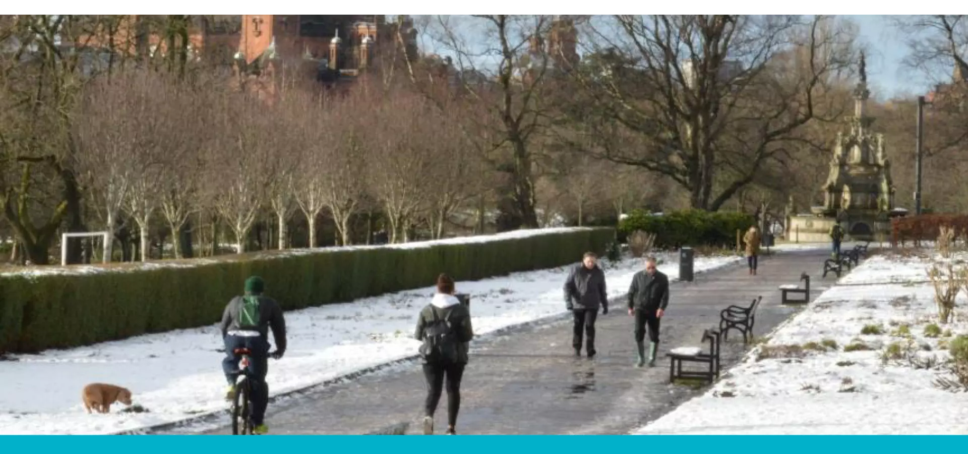 People walking and cycling in a snowy Kelvingrove park.
